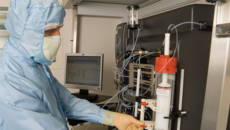 A researcher in a protective suit and face mask