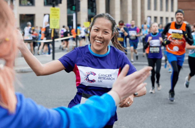 London Landmarks Racer A man running the London Landmarks Half Marathon, he is wearing glasses, a purple bandana and he is smiling.