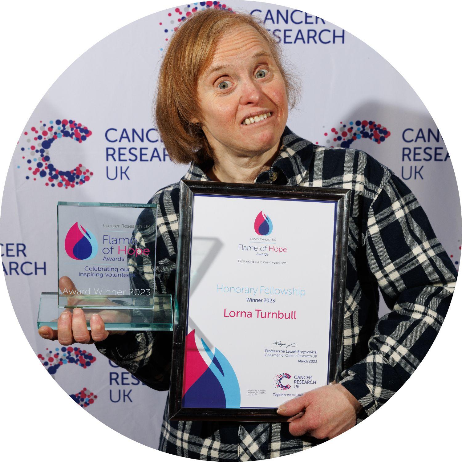 Lorna holding her Flame of Hope certificate and trophy