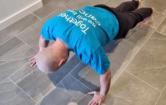 Man facing downwards on kitchen floor completing a push-up