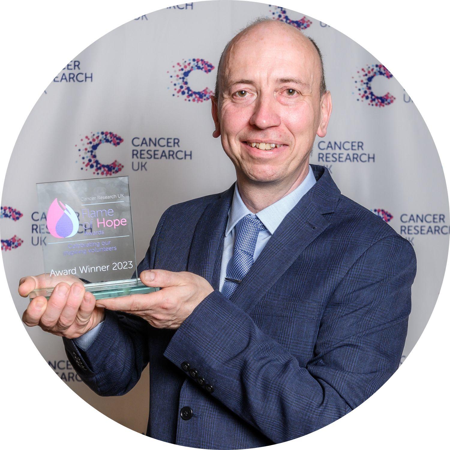 Neil holding a Flame of Hope trophy