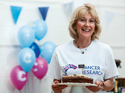 Lady in white CRUK t-shirt holding a chocolate cake