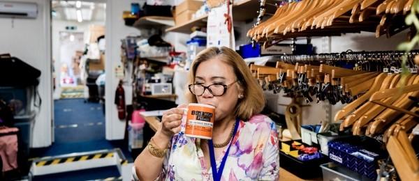 Shop volunteer in backroom drinking from a mug