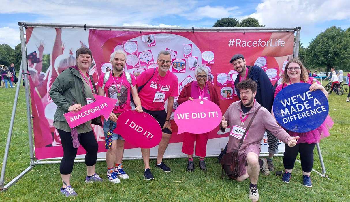 Photo of seven CRUK fundraisers posing in front of a branded banner