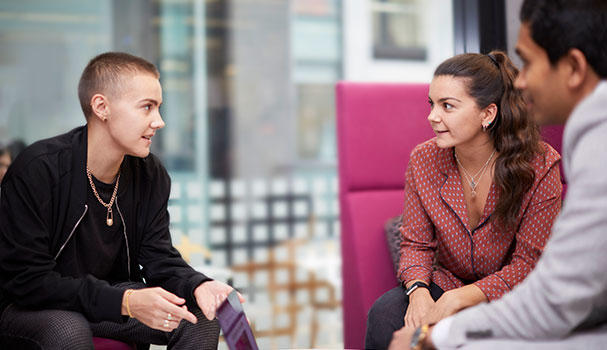 Three people sitting down and socialising in the office
