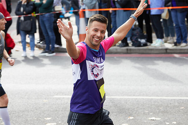 Man smiling running with arms raised