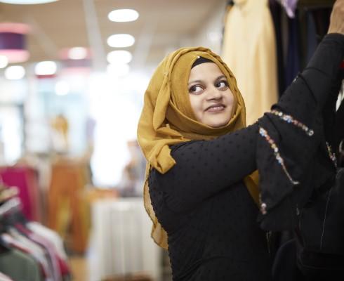 A shop worker hangs up clothes in a Cancer Research UK shop.