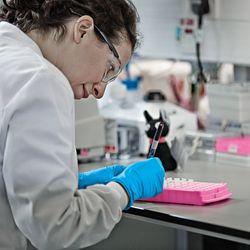 Female researcher in a lab coat pipetting in a laboratory