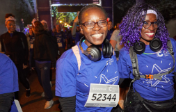 Two Shine Night Walk participants smiling into the camera, with headphones around their neck