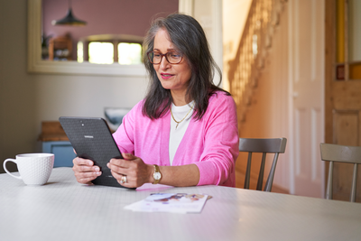 lady reading information on an electronic device whilst sat at a table. 