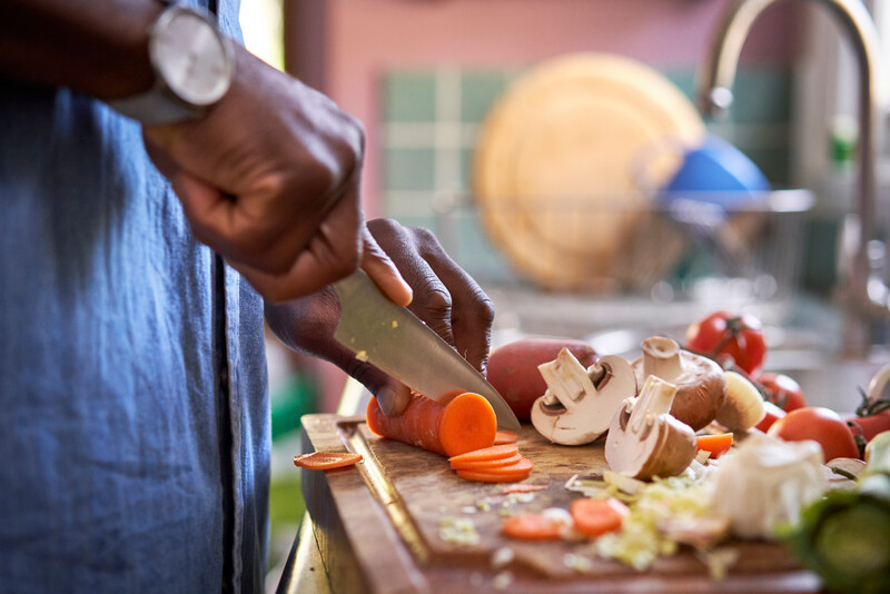 A man and woman in a kitchen cooking a healthy meal