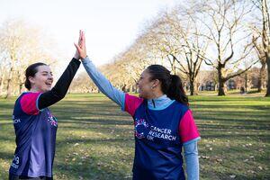 Two people wearing Cancer Research UK running tops high-fiving