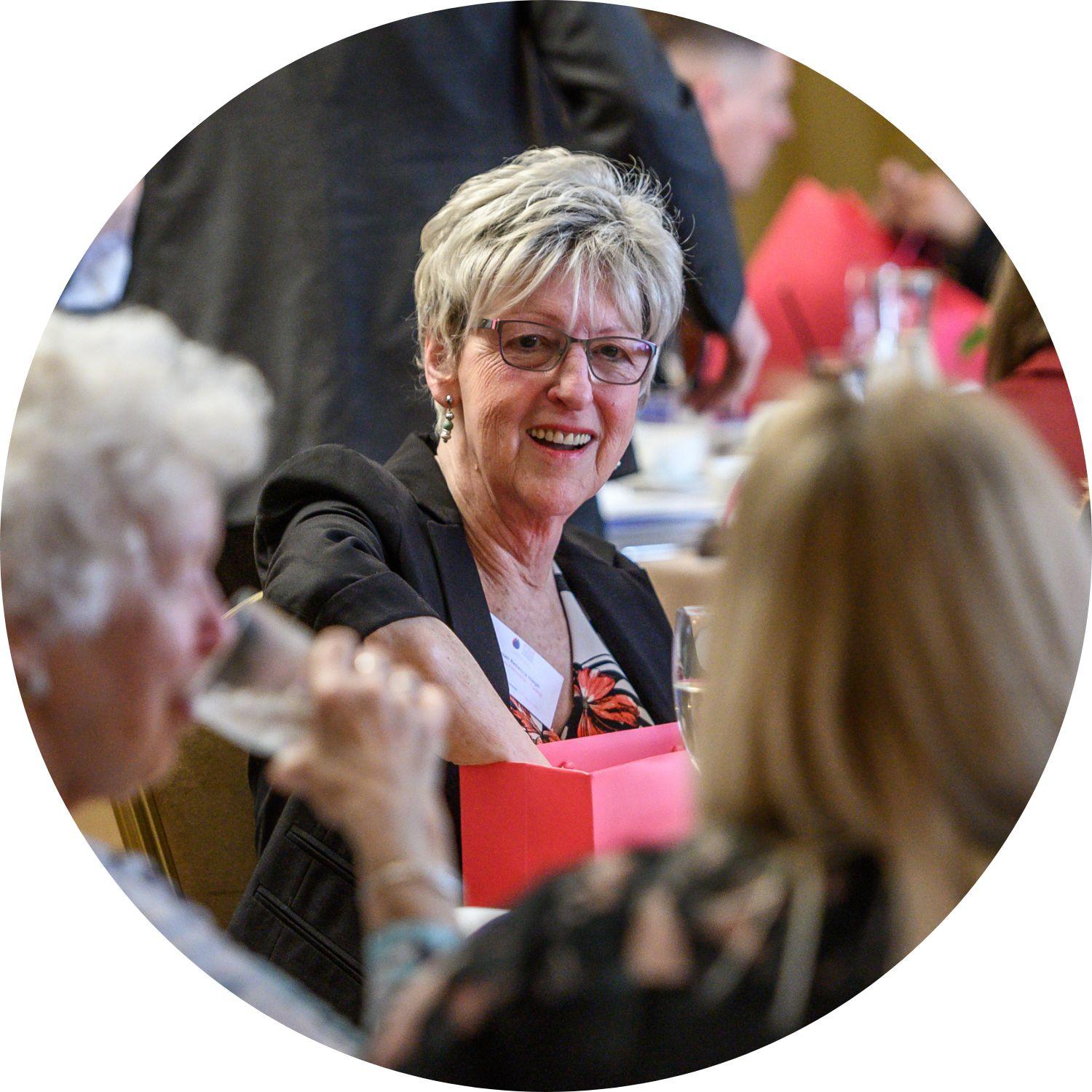Susan sitting at the Flame of Hope Awards, and smiling