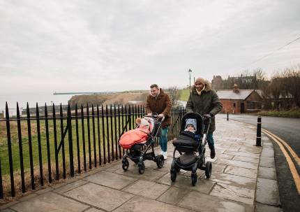 Two fathers walking with their children in prams