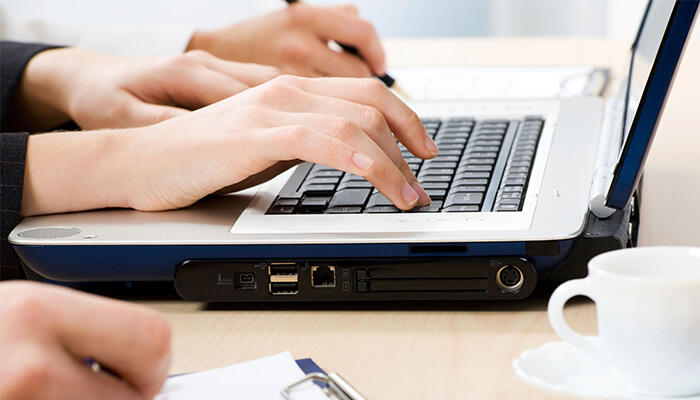 Image of someone's hand typing on a laptop