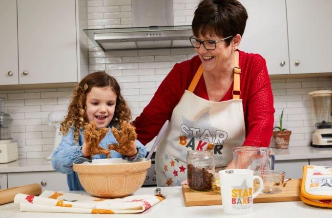A woman and child baking a cake for the bake off