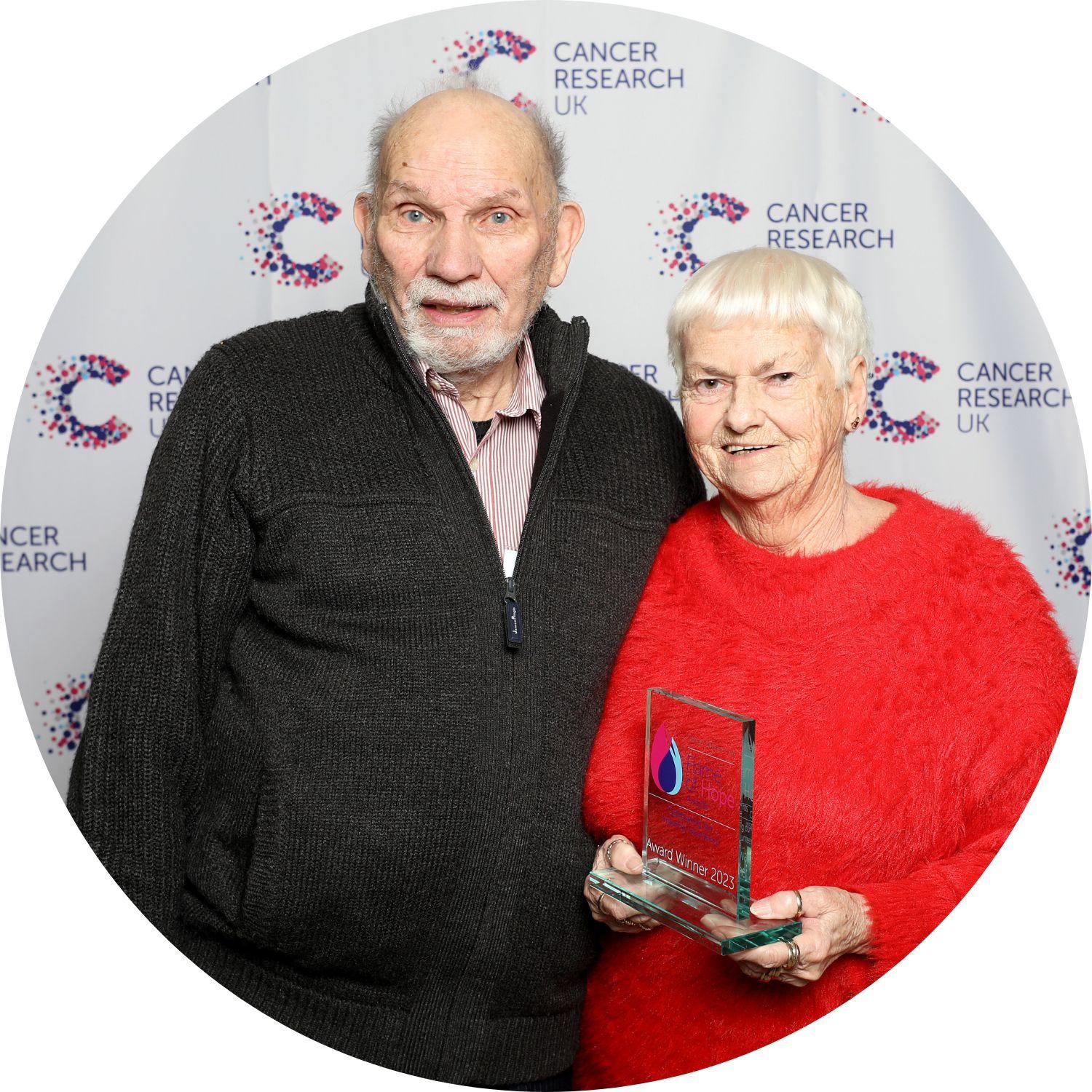 Ursula holding her Flame of Hope trophy, standing with her guest to our left