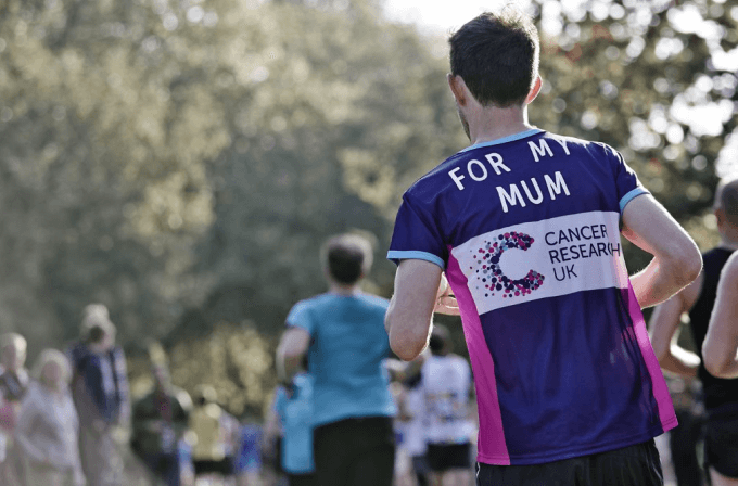 The back of a man running in a CRUK t-shirt that says 'For my mum' on it