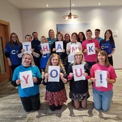 A group of people are holding up a sign saying thank you