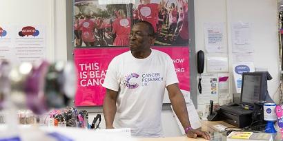 A volunteer standing at the till in a CRUK shop