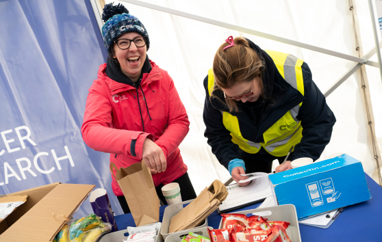 Volunteers standing behind a table laughing, whilst getting ready for an event