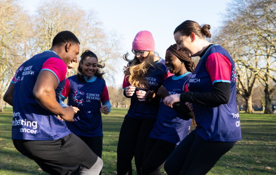 Group of volunteers standing in a circle outside, doing an exercise warm up