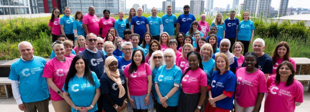 Large group of volunteers standing outside and wearing Cancer Research UK t-shirts