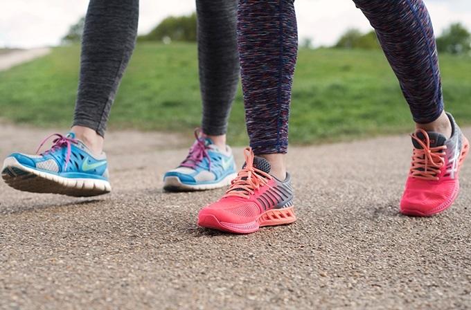 An image of two women walking wearing trainers