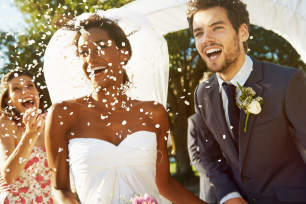 Fundraise at your wedding for Cancer Research UK. Couple smiling with confetti over them.