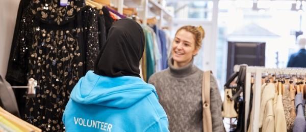 Volunteer talking to shopper between rails of clothing