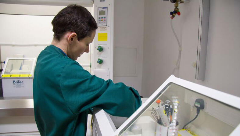 A researcher in a green lab coat in a lab