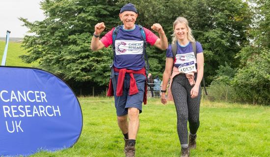 Two hikers at the Big Hike finish line waving and smiling