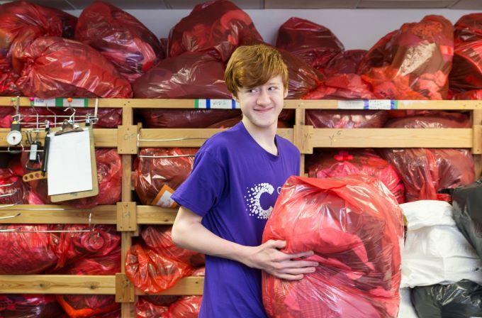 Volunteer assisting in our hub, carrying an orange sack of donated items