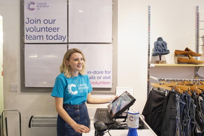 Female shop volunteer working at the till