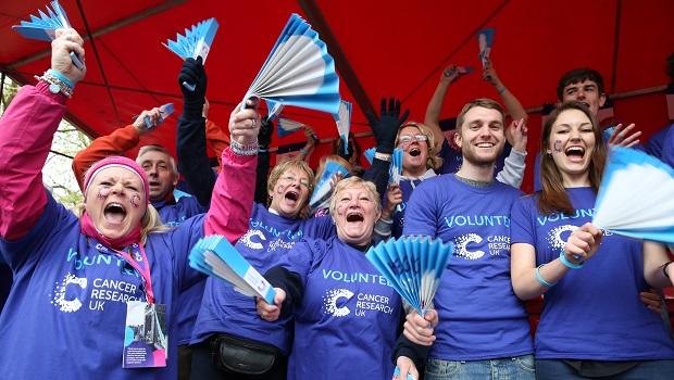 Cancer Research UK Cheer Team waving banner and cheering at London Marathon.