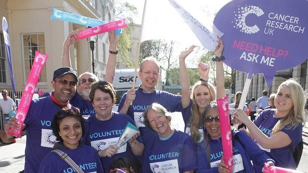A group of volunteers in a group wearing Cancer Research UK tops and celebrating
