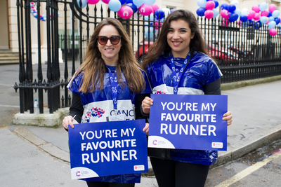 Two female race marshals with 'you're my favourite runner' signs