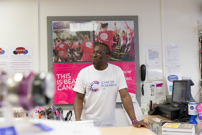 Male volunteer standing at the till on a CRUK shop