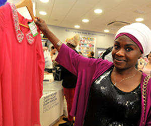 A photo of a customer at a charity shop holding up a top donated to Cancer Research UK
