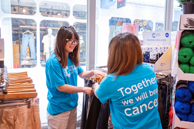 2 volunteers in shop, 1 person handing items to another
