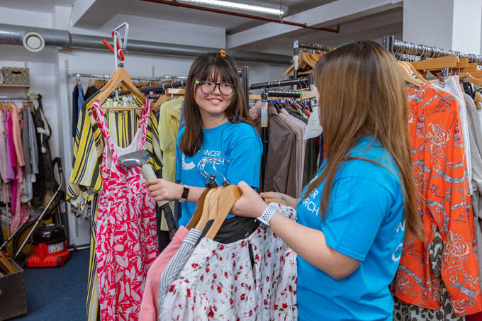 Volunteers smiling whilst steaming clothes in the shop