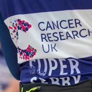 Runner wearing a CRUK vest with back to camera at a post race event.