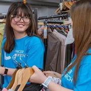 Two volunteers hanging up and sorting clothes on CRUK shop floor