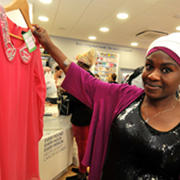A photo of a customer at a charity shop holding up a top donated to Cancer Research UK