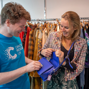 A male shop volunteer smiling and talking with a female customer 