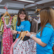 Volunteers smiling whilst steaming clothes in the shop